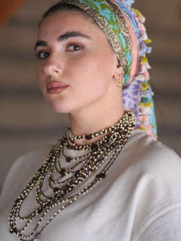 Square scarf with colorful print, pink pom-poms, and a panther stripe.